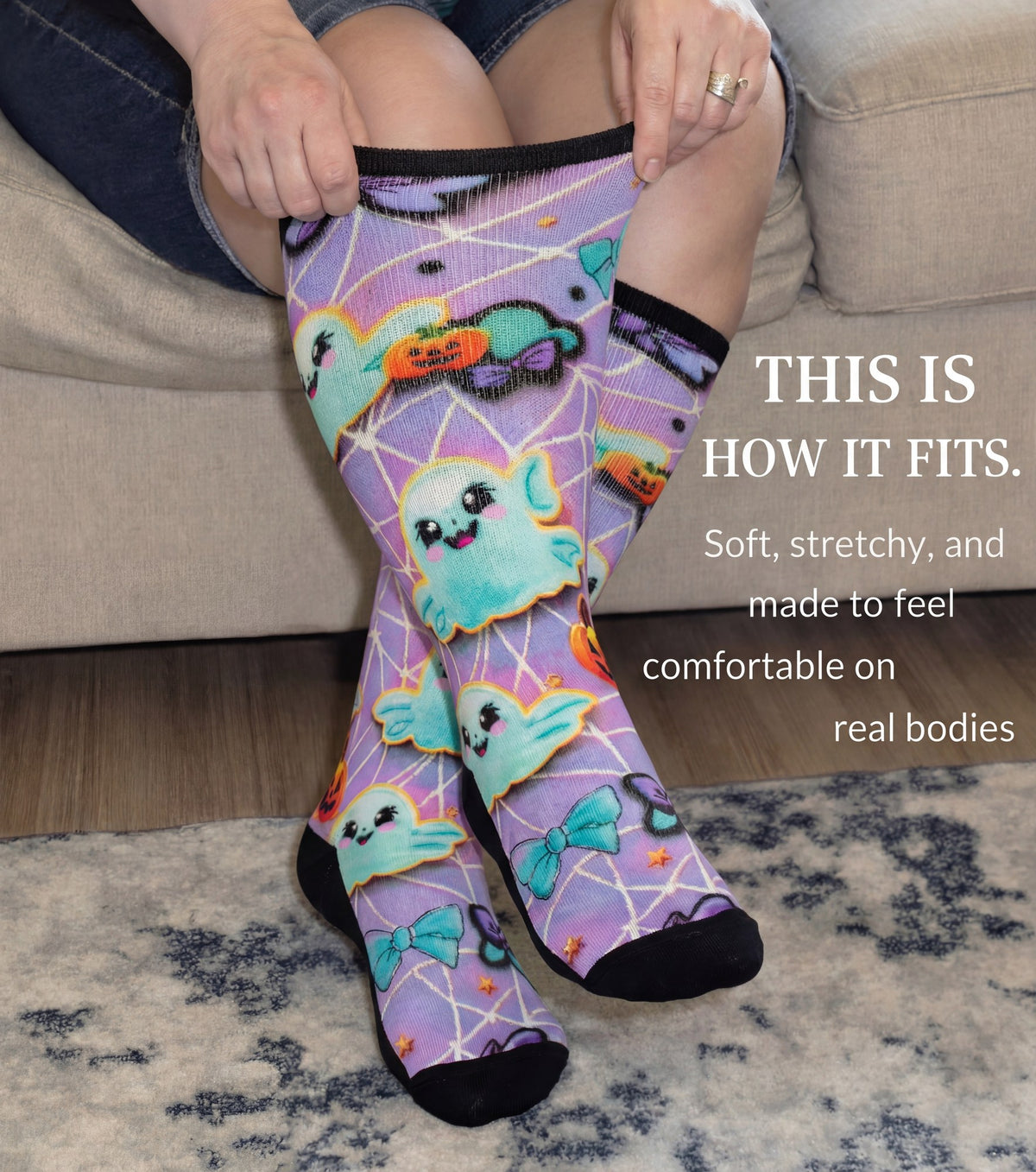 Woman stretching the cuff of Gooi Halloween extra wide socks, purple ghost print, non-binding fit