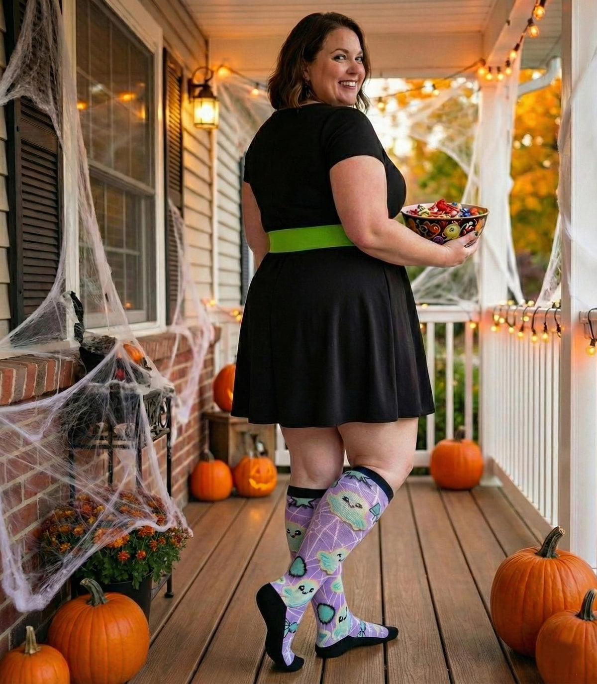Woman on a decorated Halloween porch in Gooi purple ghost extra wide socks