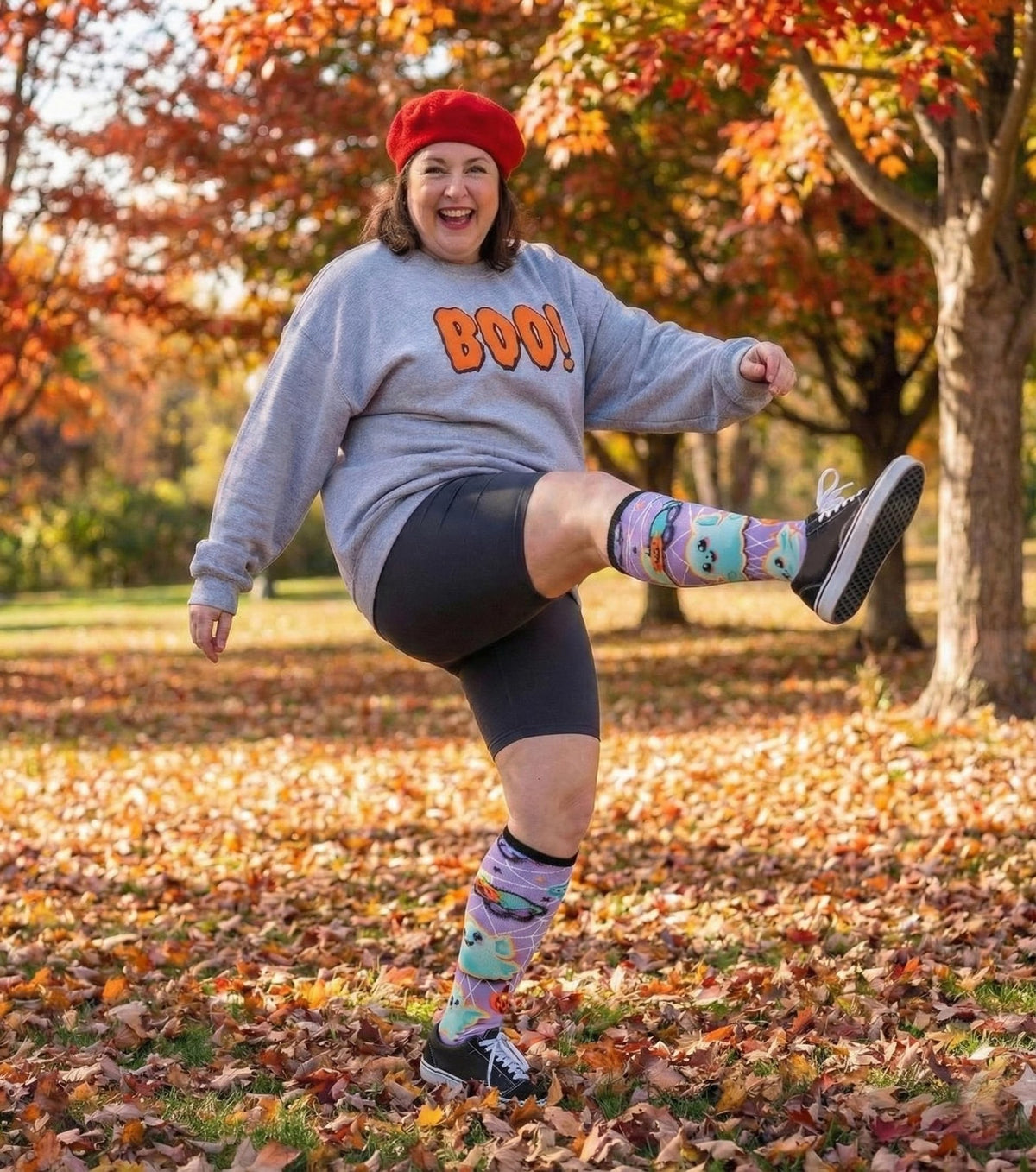 Woman kicking in autumn leaves wearing Gooi Halloween extra wide socks, stays up, no digging